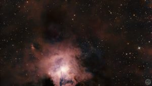 Fotografia astronómica profunda exibindo a Nebulosa da Íris (NGC 7023) no centro, caracterizada por um núcleo estelar brilhante intensamente rodeado por delicadas e complexas nuvens de poeira reflectora de tons azuis e anil. Todo o campo em torno da nebulosa revela extensas e imponentes massas de poeira escura e acastanhada que bloqueiam a luz de fundo. A imagem encontra-se ponteada por estrelas nítidas de diversas colorações sobre um céu negro e profundo.