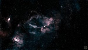 Fotografia astronómica de campo amplo destacando um enorme anel incompleto de gás vermelho rubro com a forma de uma garra, correspondente à nebulosa SH2-157. A estrutura gasosa é complexa, densa e esculpida, destacando-se veios mais escuros de poeira. No quadrante inferior esquerdo brilha uma nebulosa secundária bastante compacta e intensa (NGC 7538). O fundo negro do espaço é imaculado, salpicado por estrelas pontuais perfeitas cujas cores individuais se mantêm bem preservadas.